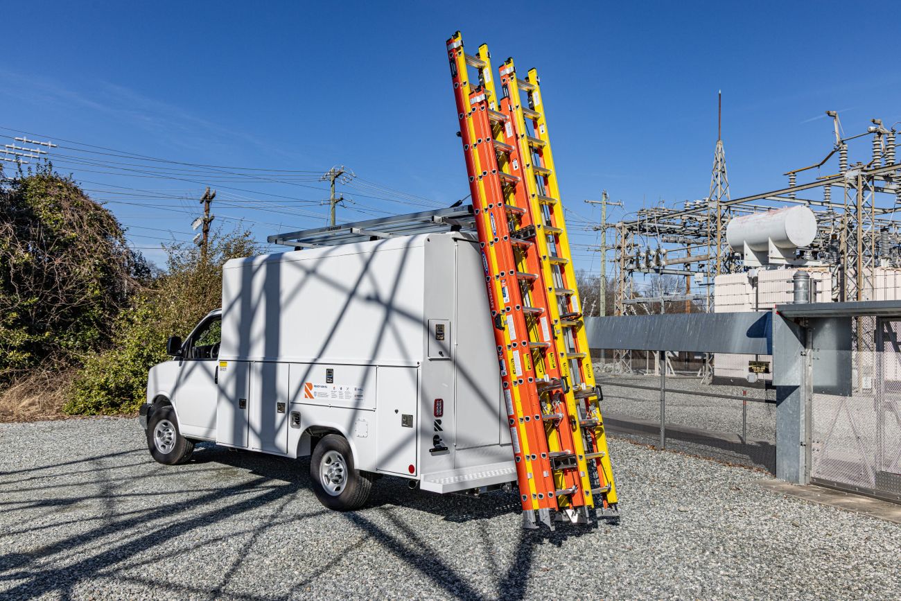 white step van with drop down ladder rack on top with ladders lowered to the ground