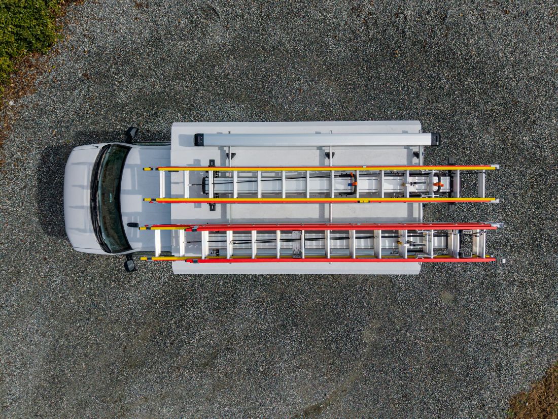 roof of work van with 4 ladders on drop down ladder rack