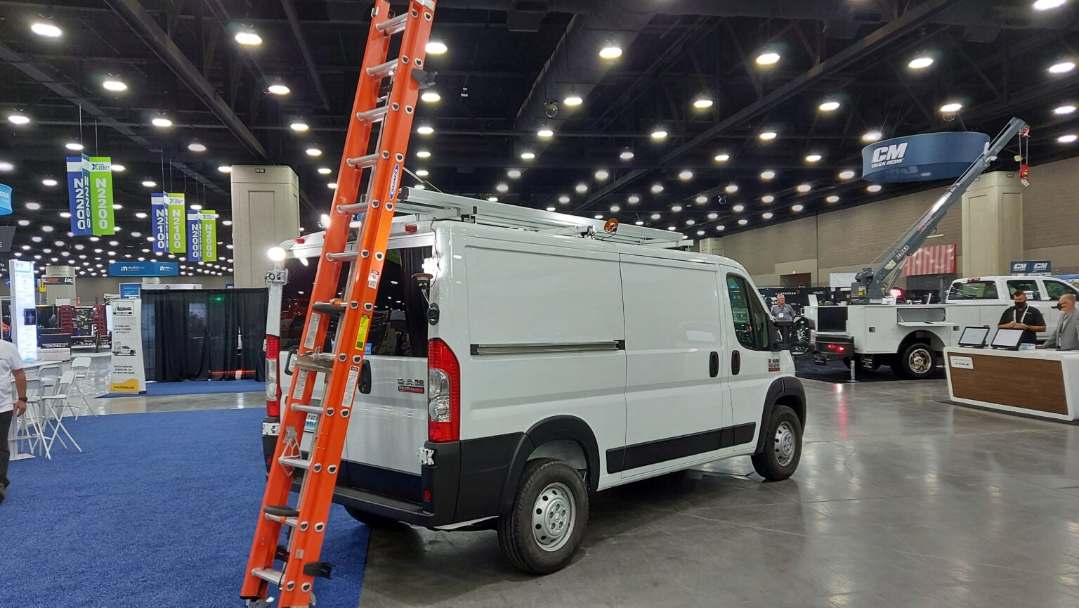 white ram promaster work van at trade show with drop down ladder rack with orange ladder