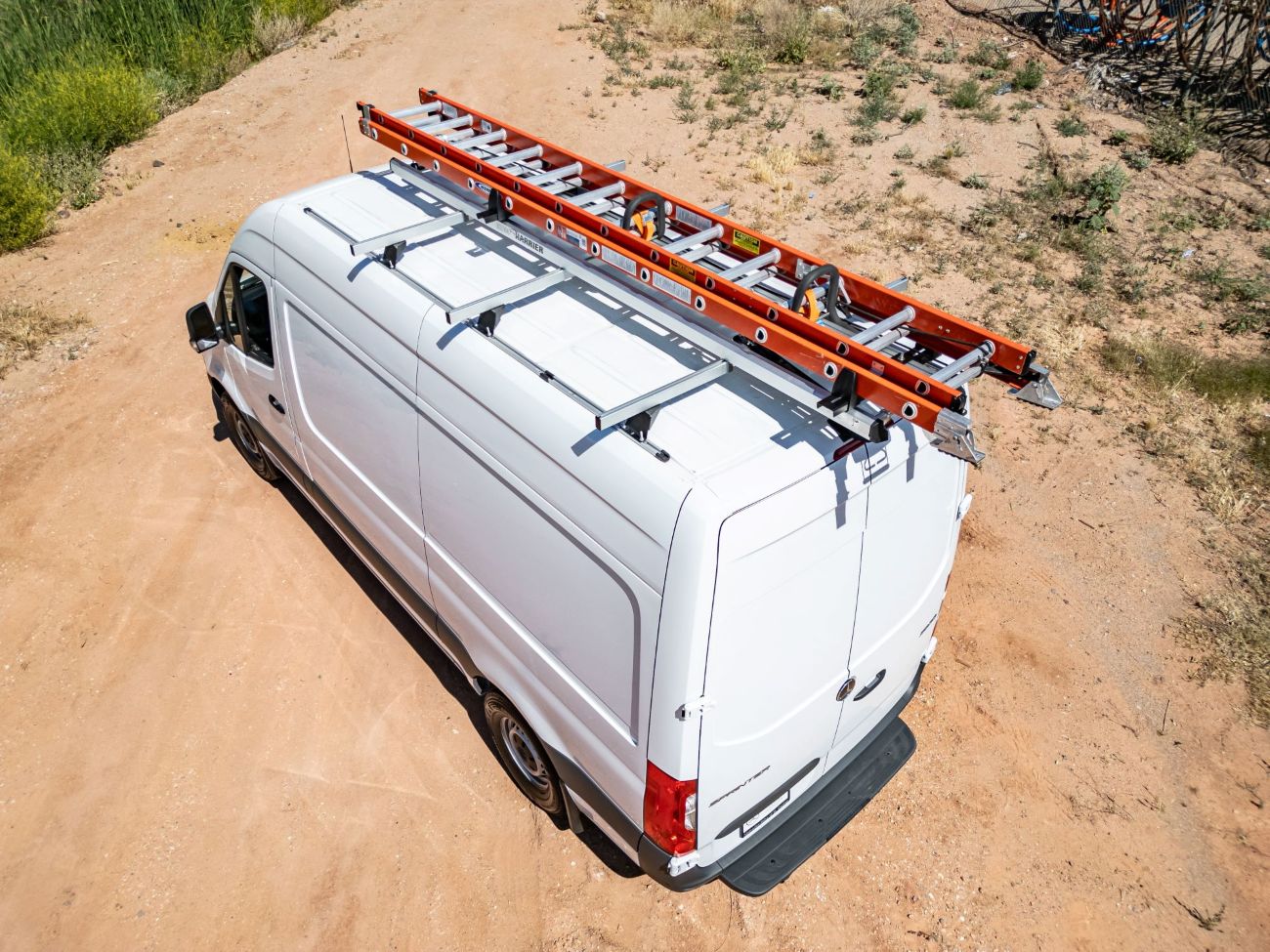 white work commercial fleet van with orange ladder on drop down ladder rack