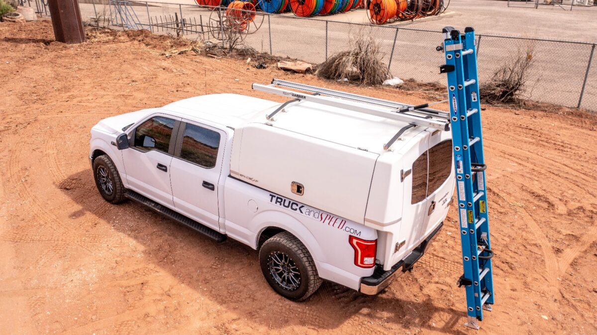 white work truck with topper cap and drop down ladder rack