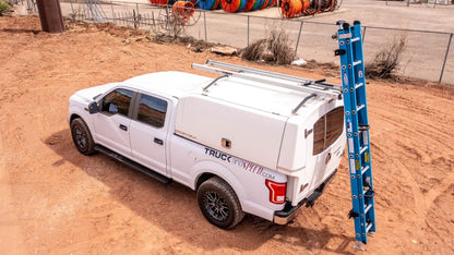 white work truck with topper cap and drop down ladder rack
